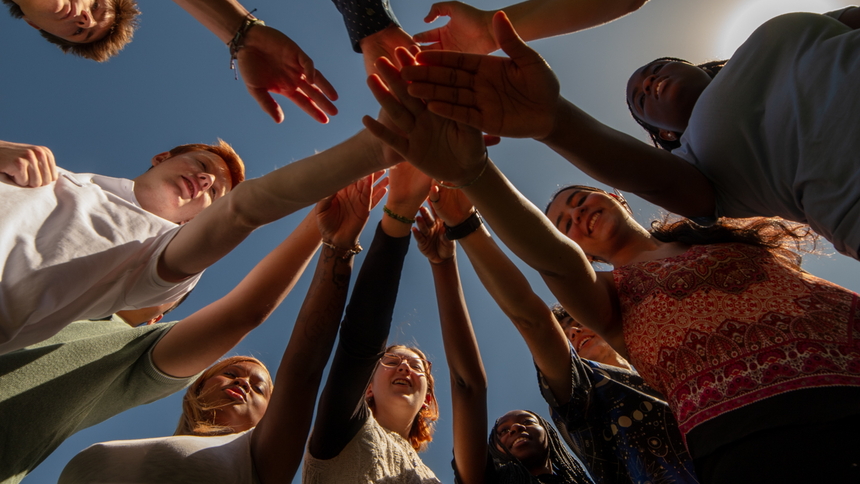 Go team on three! Looking up at interns with hands in during an early internship huddle. 