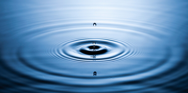 Water droplet ripples outward in blue water