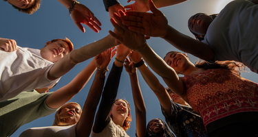 Go team on three! Looking up at interns with hands in during an early internship huddle. 