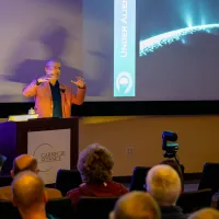 Phil Plait holds his hands up illustrating the pressures that led to Enceladus' fissues