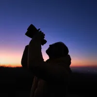 amateur astronomer looks at the sky with binoculars