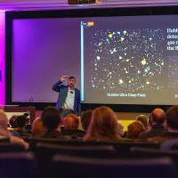John Mulchaey stands in front of screen with JWST image