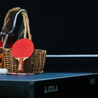 The ping pong table on a black background with a basket of supplies sitting on top. 