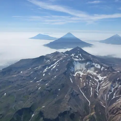 Image of four mountain peaks above a solid white cloud cover
