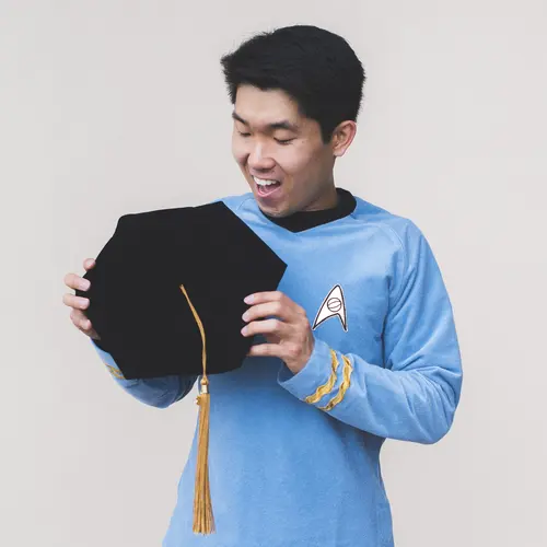 Mike Wong holds his PhD graduation cap in a Star Trek uniform