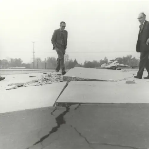 Charles Richter (right) and others viewing buckled pavement.
