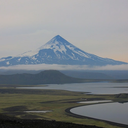 A view over Fisher Caldera in the foreground, looking out to Shishaldin Volcano, at a distance in 2015. The gray and gloomy tone of the photo is characteristic of the weather in the Aleutian Island. Photo is courtesy of Daniel Rasmussen of the National Museum of Natural History. Photo taken under Alaska Maritime National Wildlife Refuge Research and Monitoring Special Use Permit #74500-15-011.