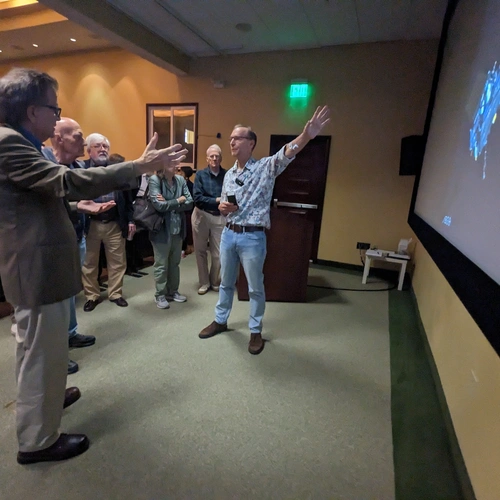 Conel holds his hand up toward a meteorite sample during a discussion with neighborhood guests at the end of his Neighborhood Lecture