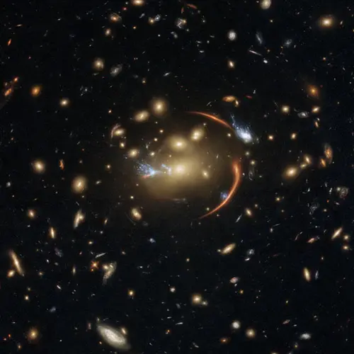 This Hubble image shows the galaxy cluster MACS J0138.0-2155, which is so massive that its gravity bent and magnified light streaming not only from an extremely distant background galaxy but also from a supernova event in this galaxy. The color image was made using observations from eight different filters spread across Hubble’s Advanced Camera for Surveys (ACS) and Wide Field Camera 3 (WFC3). The color results from assigning different hues to each monochromatic image associated with an individual filter. I
