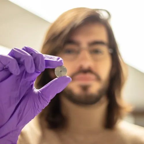 Julien Rojas holds up a sample while wearing purple nitrile gloves