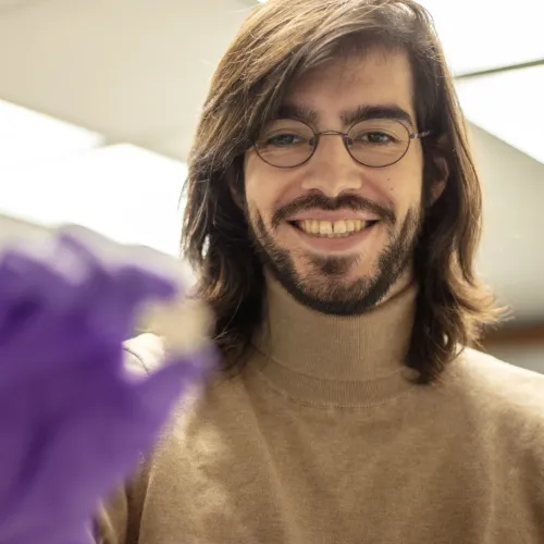 Julien Holds a Sample and Smiles at Camera