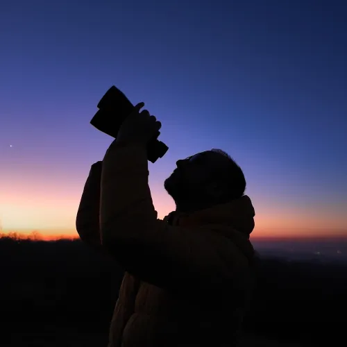 amateur astronomer looks at the sky with binoculars