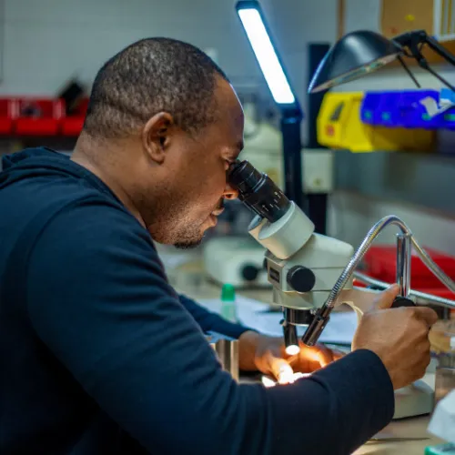 Postdoc Innocent Ezenwa looks through a microscope at the Earth & Planets Laboratory
