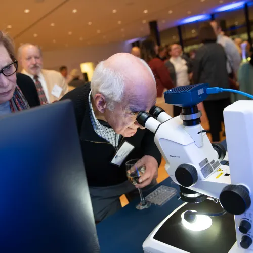 Carolyn and David Gambrel look through a microscope at a Donor Appreciation Event held after a Capital Science Evening lecture by Dr. Margaret McFall-Ngai