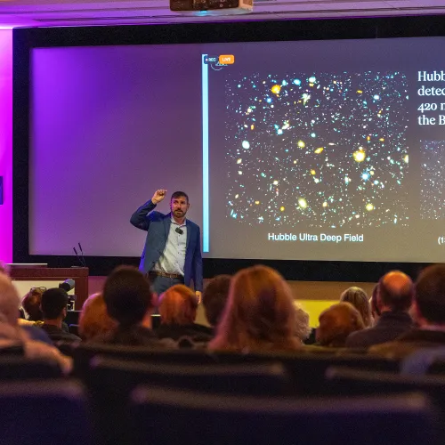 John Mulchaey stands in front of screen with JWST image