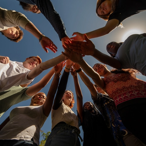Go team on three! Looking up at interns with hands in during an early internship huddle. 
