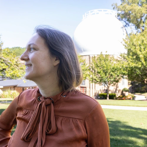 Marion Le Voyer looks to the left in front of the Atomic Physics Observatory